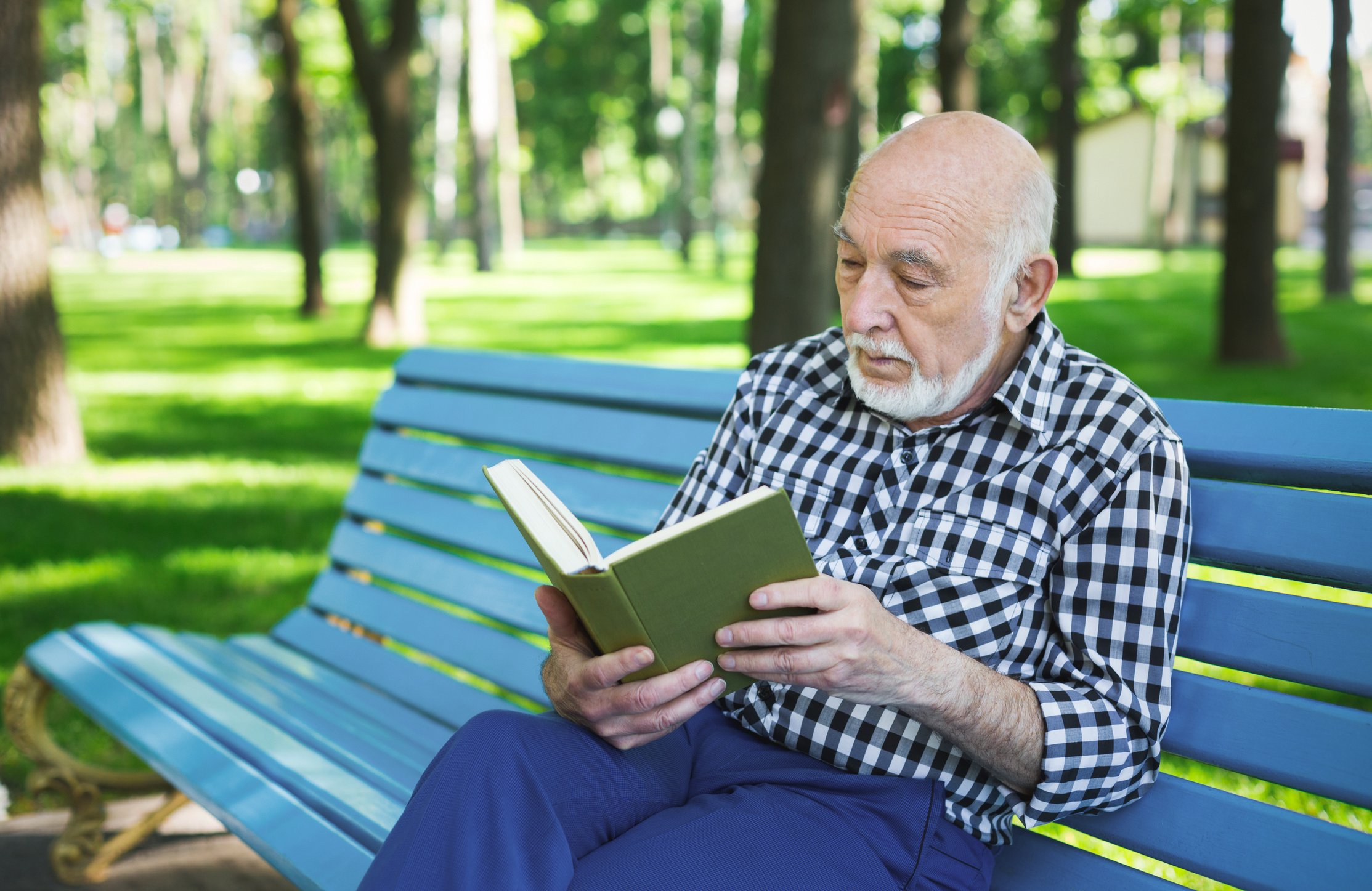 Elderly man in casual reading outdoors